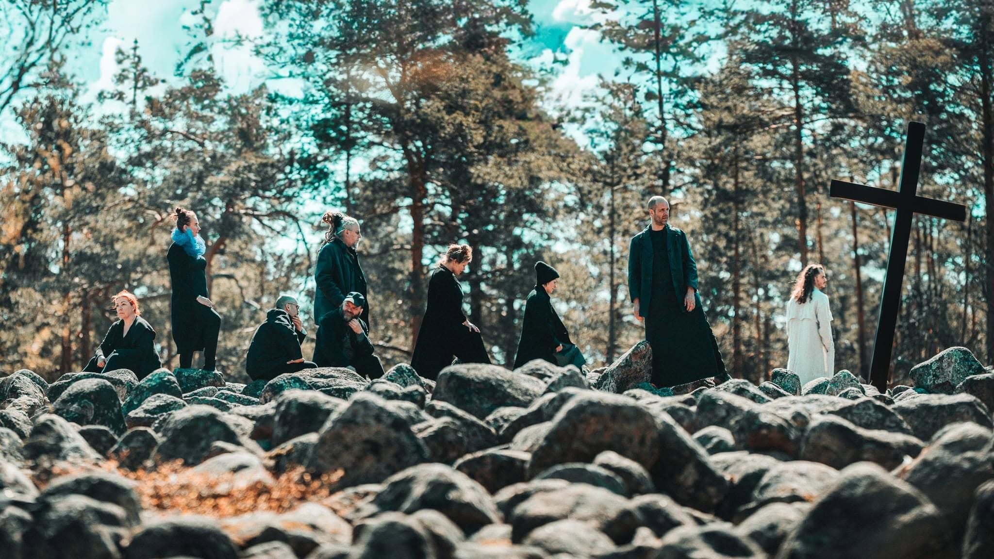 The black-clad ensemble of St Matthew Passion walking through a rocky landscape