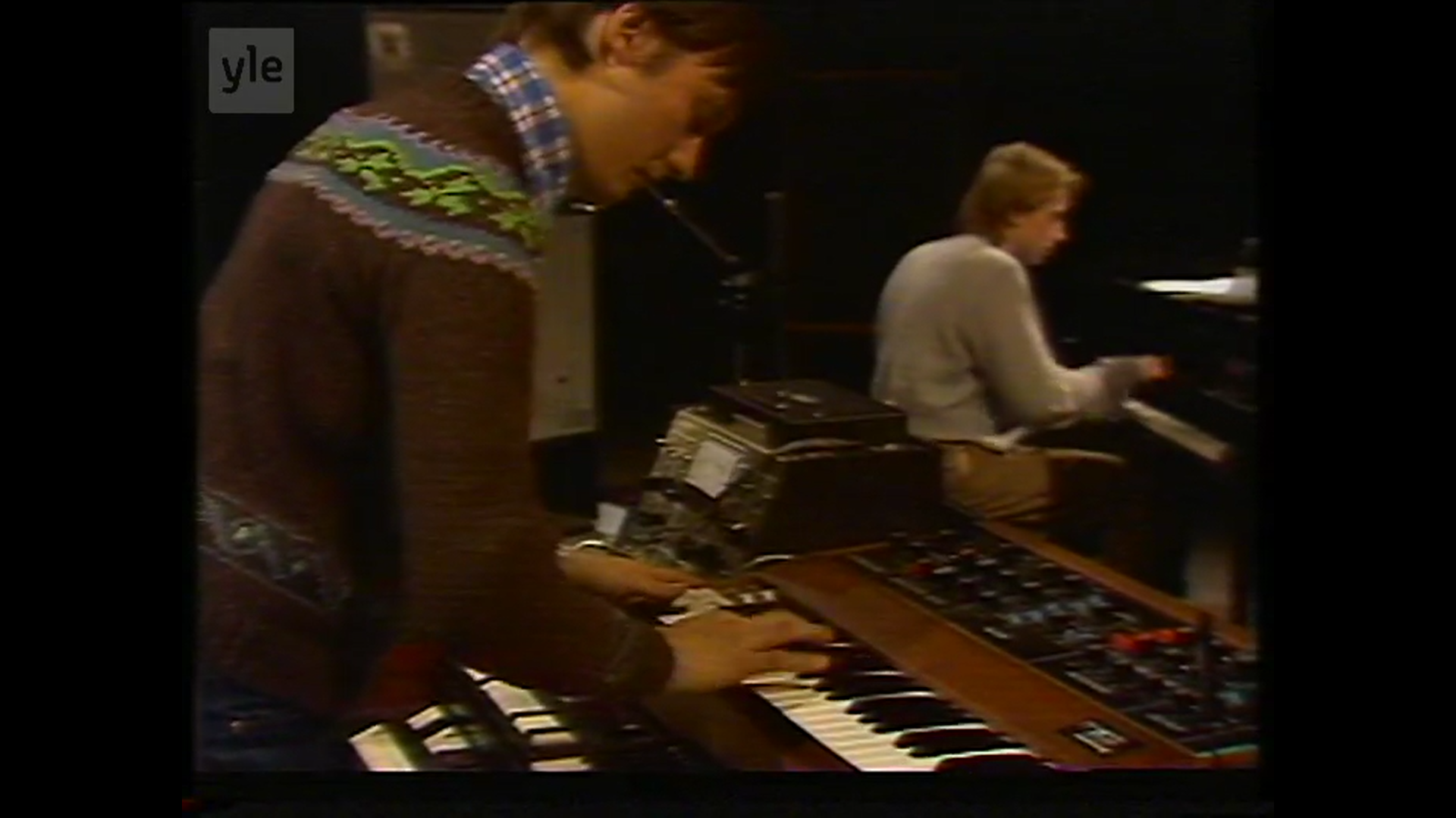 Jukka Gustavson playing Moog in the foreground and Ismo Laakso at the grand piano with Ismo Laakso Group in a Yle television programme